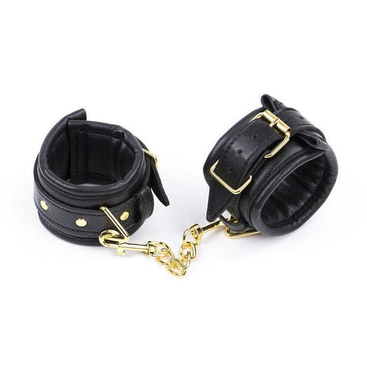 Black BDSM handcuffs with gold chain and buckles