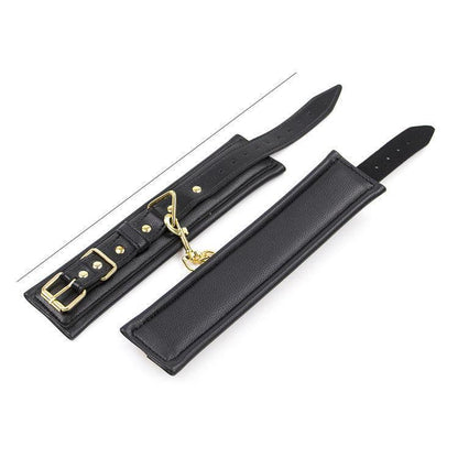 Black BDSM wrist restraints with gold buckle