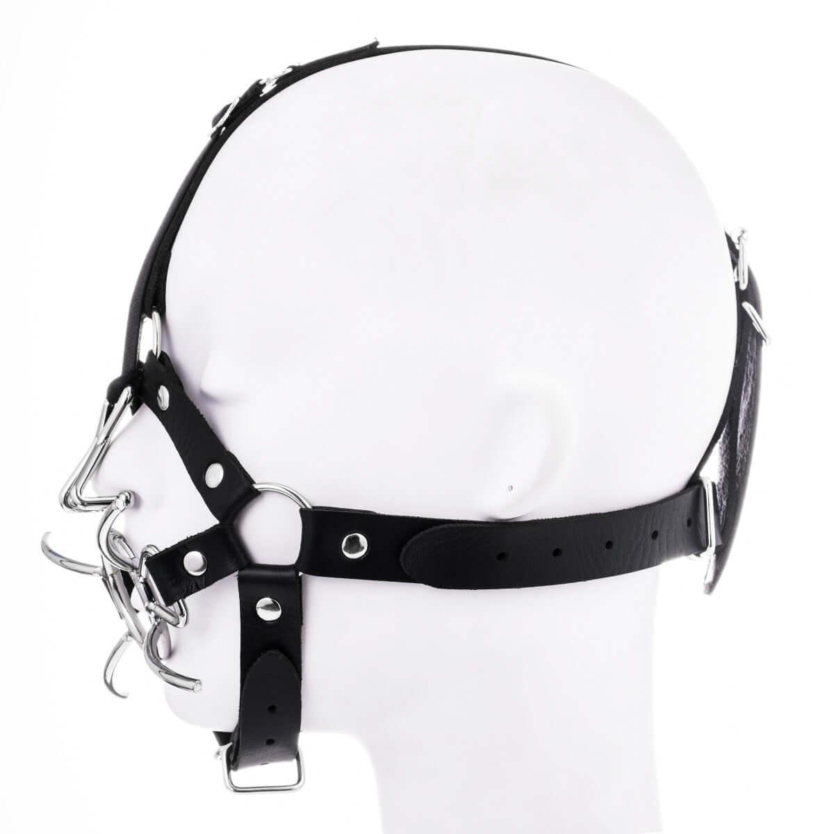 Mouth gag with nose hook harness in black leather, featuring metal rings and straps for restraint and domination fantasies.