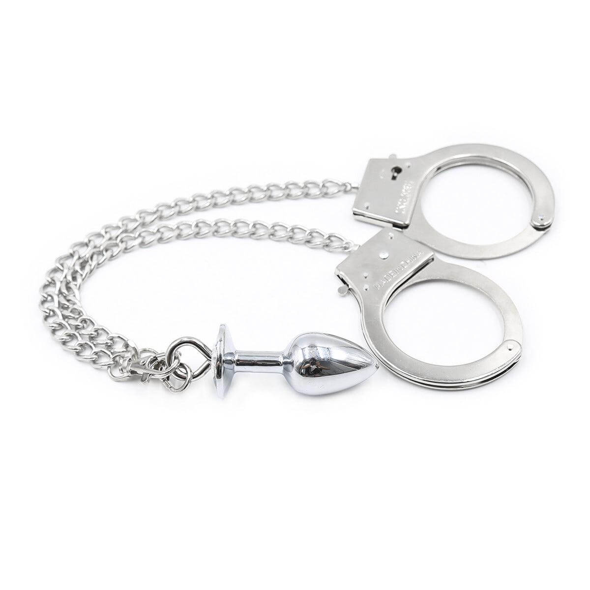 Close-up of stainless steel cuffs and anal plug with chain